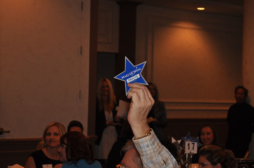 One of the guests raises their Make-A-Wish star in the air to show that they wanted to donate money.