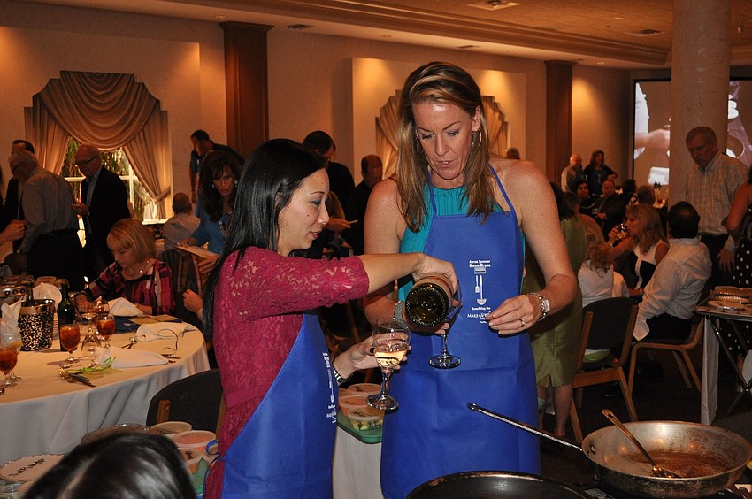 Linda Doan and Michelle Reilly pour themselves some wine before getting started cooking.