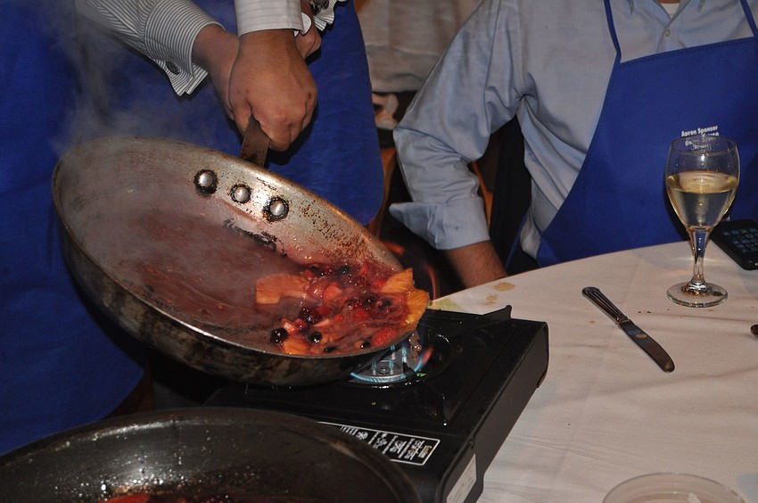 Ryan Skzypowski flambÃ©s the fresh fruit in his pan.