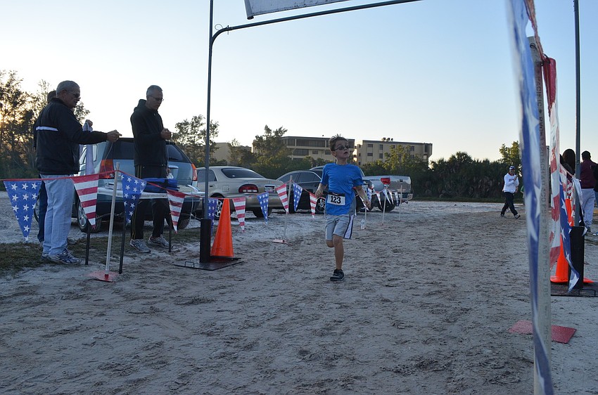 Camden Woznak, 8, checks his time as he runs into the finish line.