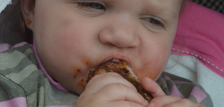 Annnabelle Bailey, 15 months, sucks on a barbeque rib.
