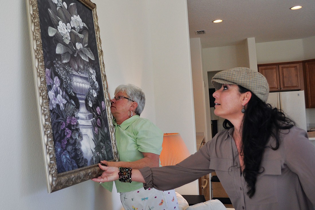 Wanda Colon shows Aletta Chapman, a student at The Academy of Home Staging, how to hang a painting.