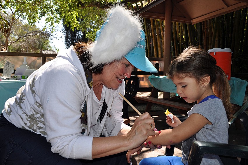 Monique Ring paints a rainbow and star on Jasmin Flowerâ€™s, 4, arm.
