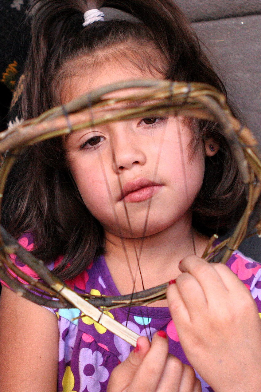 Ndezolth Sauceda, 6, works on making a dream catcher as she sits in the trunk of her familyâ€™s van. Saucedaâ€™s family traveled all the way from Santa Fe, NM to attend the festival.