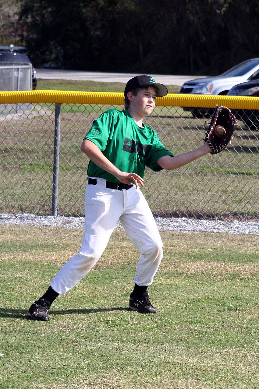Jake Peterman, 12, catches a ball thrown by one of his teammates during warm ups.