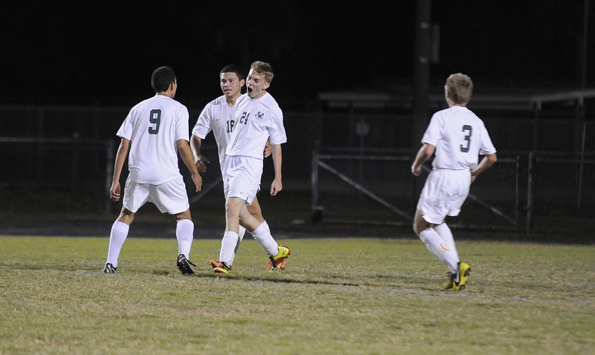 Members of the Lakewood Ranch High boys soccer team celebrate following forward Ryan Sollazzoâ€™s second goal of the match.