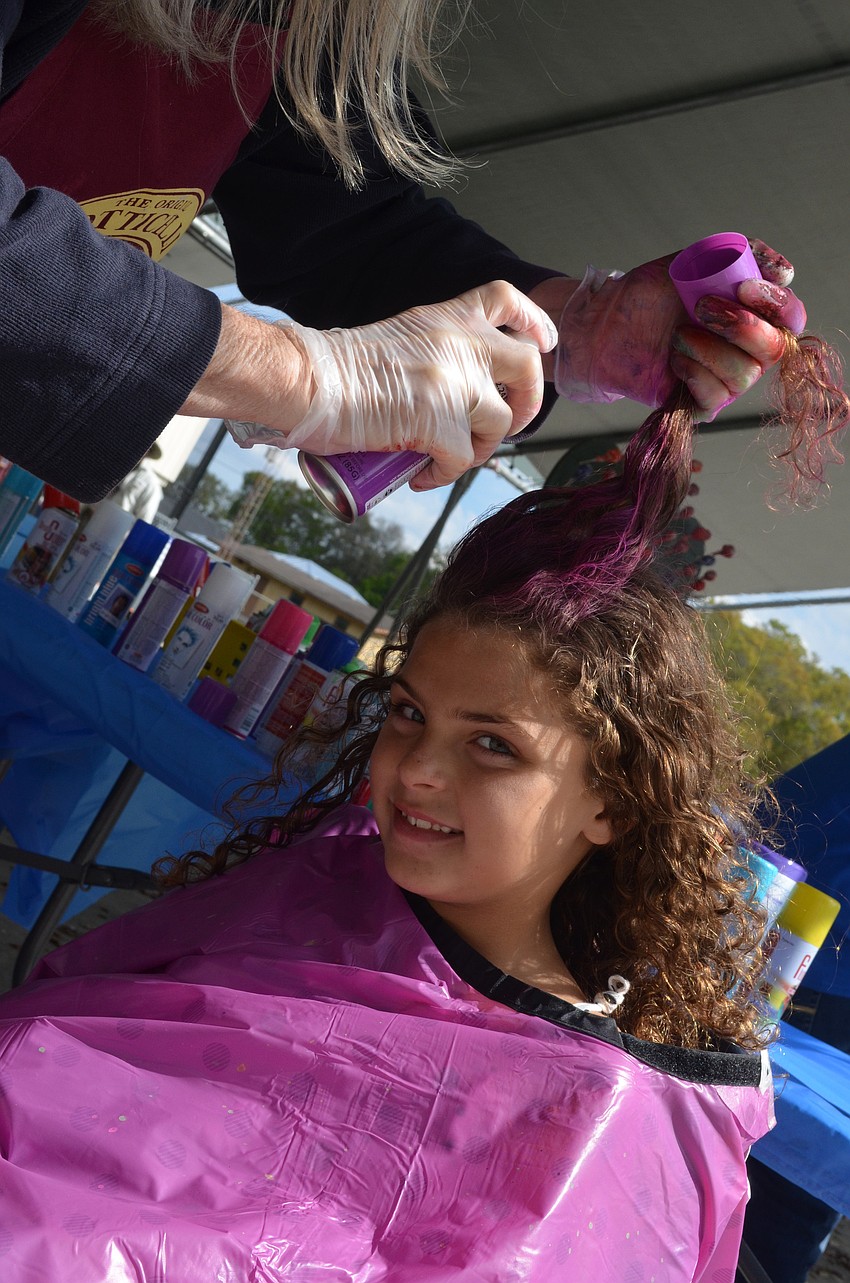 Maya Stutzman, 7, gets her hair colored purple at the festival.
