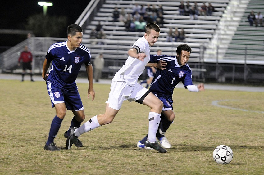 Lakewood Ranch defender Jason Ferguson battles Manatee Highâ€™s Carlos Reyes and Johnny Salgado for possession.