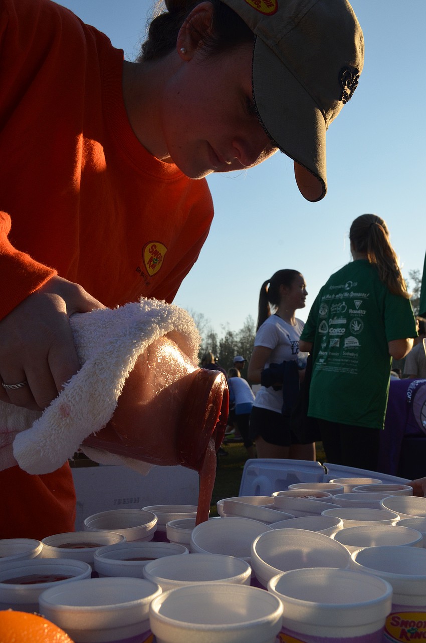 Abby Blow pours Smoothie King smoothies into little cups for racers and volunteers. Smoothie King was one of the sponsors of the event.