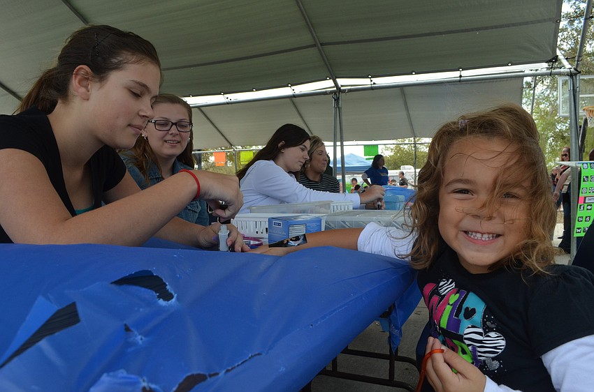 Taylor Kennell, 15, stencils a drawing on her five- year-old sister Makaylaâ€™s hand.