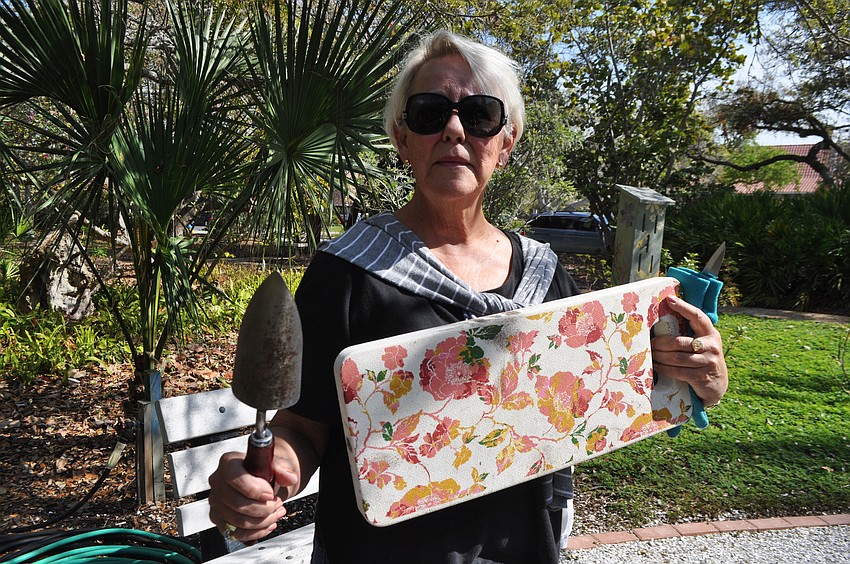 Celia Edmundson holds up the tools of the trade, a trowel and a knee guard.