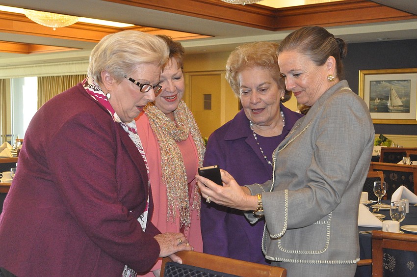 Cynthia Stepp, Kathleen Powell, Judy Weinstein and Trudy Barry look at photos of flower arrangements on Barryâ€™s phone.