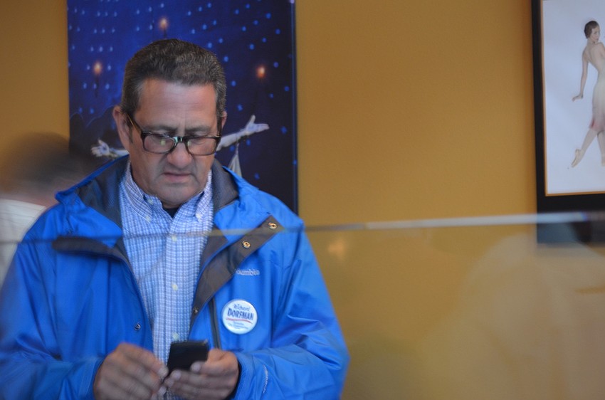 Richard Dorfman checks his phone for results.