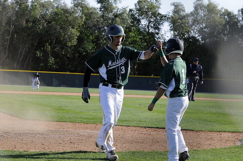 Brandon Lam, right, congratulates Justin Greenway after he scored a run midway through the Mustangs pool play game versus North Port March 25.