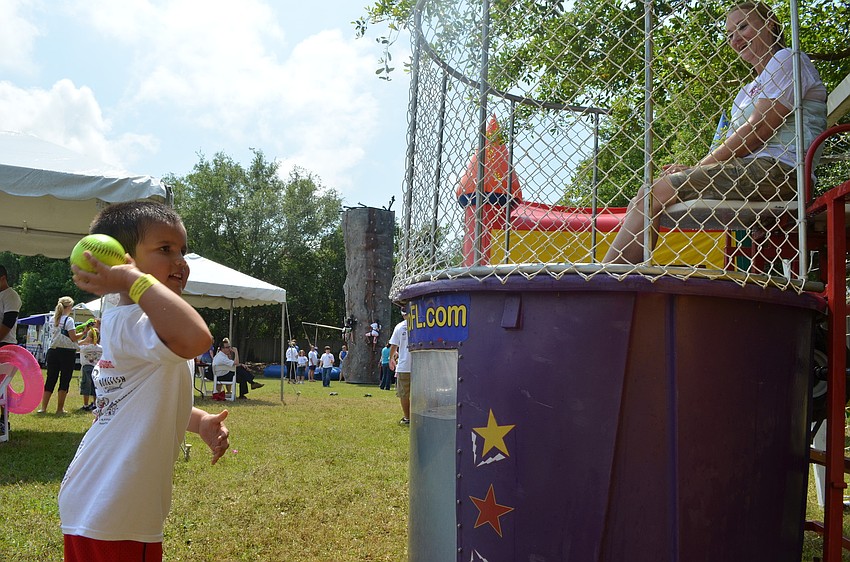 Tamas Torek throws a ball in hopes of dunking kindergarten teacher Sandra Larson.