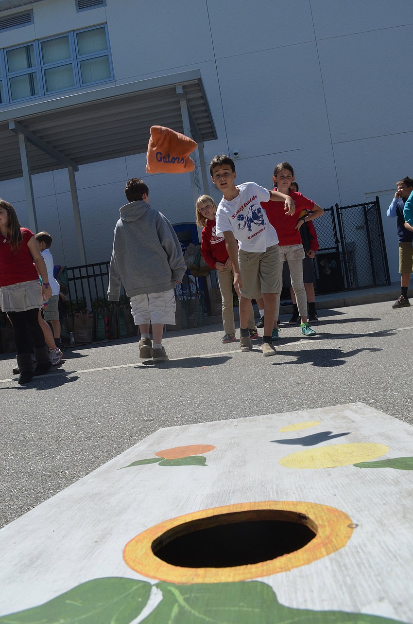 Fifth grader Chris Tocher tosses a beanbag in a corn hole game at the Browns Grove zone.