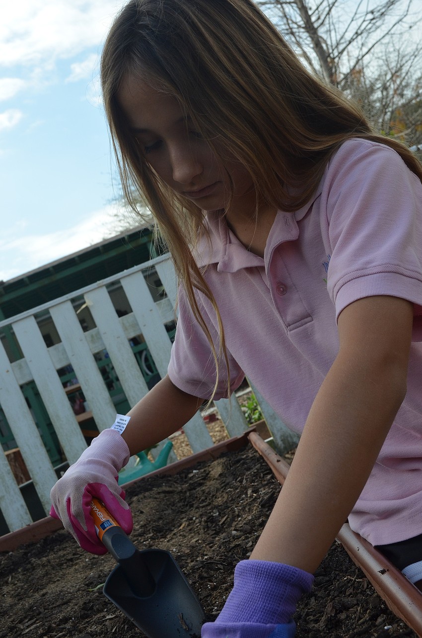 Nina Edelsbacher, 10, digs a hole to place her plant.