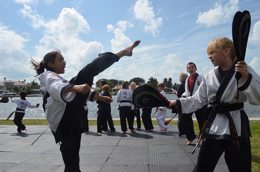 Cassidy Lawless, 9, holds up kicking pads for Amber Riggs, 11. They are both students at Mingwu Martial Arts.