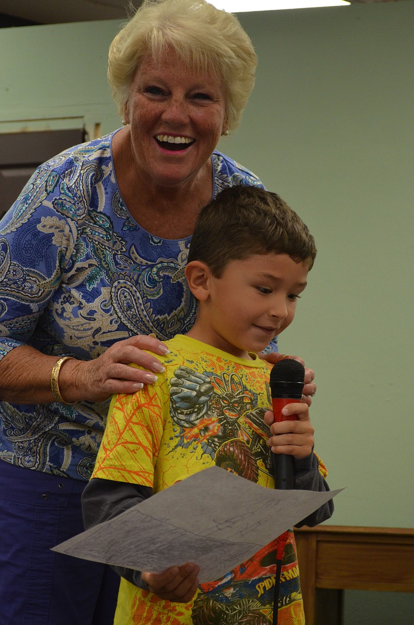 Preschool teacher Kathy Polen helps preschooler Christopher Catlin share his picture and talk about why he loves his grandparents.