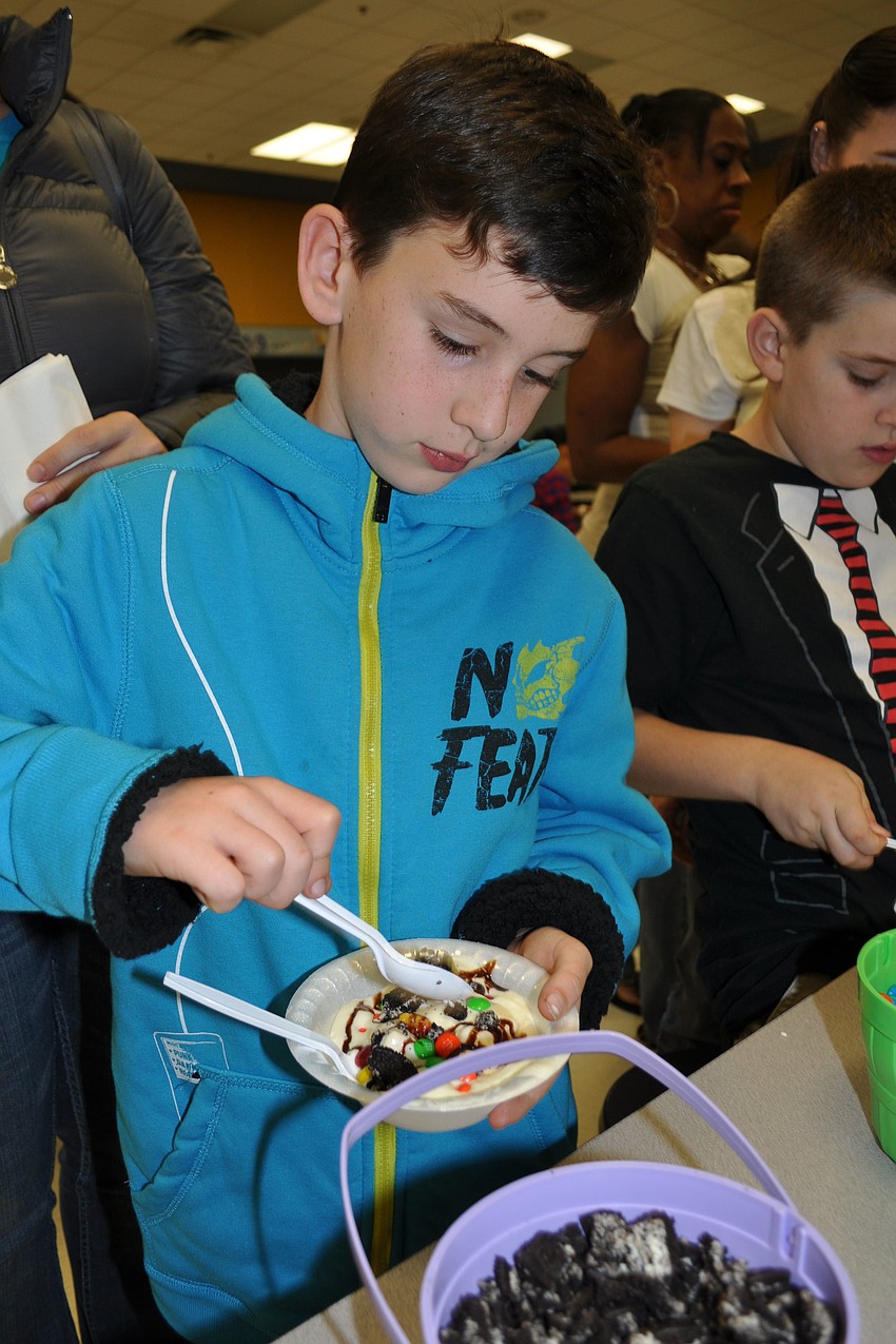 Harrison Bakker, 9, tops his ice cream with Oreo crumbles, M&Mâ€™s, one gummy bear and chocolate syrup.