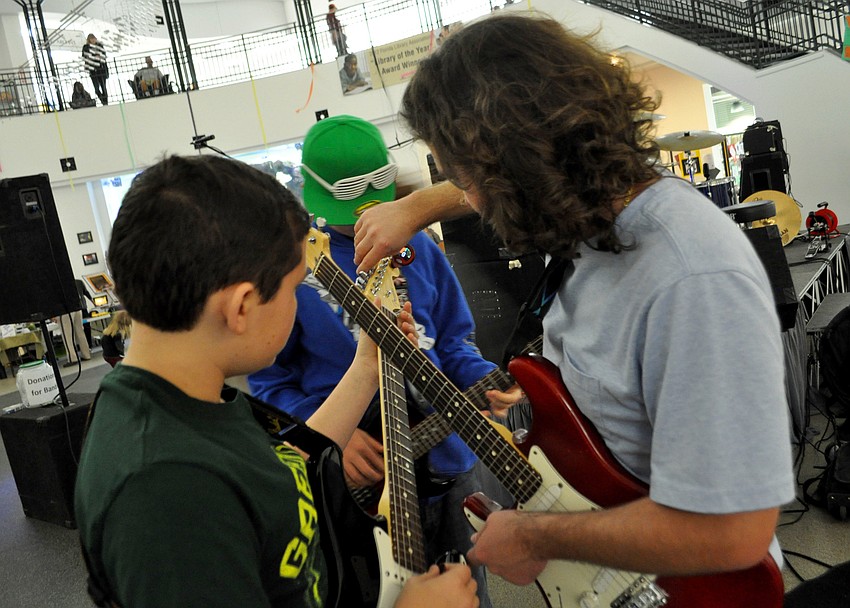 Gene Hodsdon helps Jonah Mundy tune his guitar.