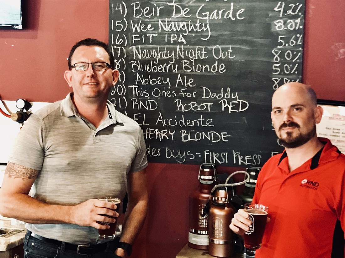 RND Automation & Engineering President and CEO Sean Dotson, left, and mechanical engineer Chad Malone, right, with RND Robot Red at Naughty Monk Brewery.