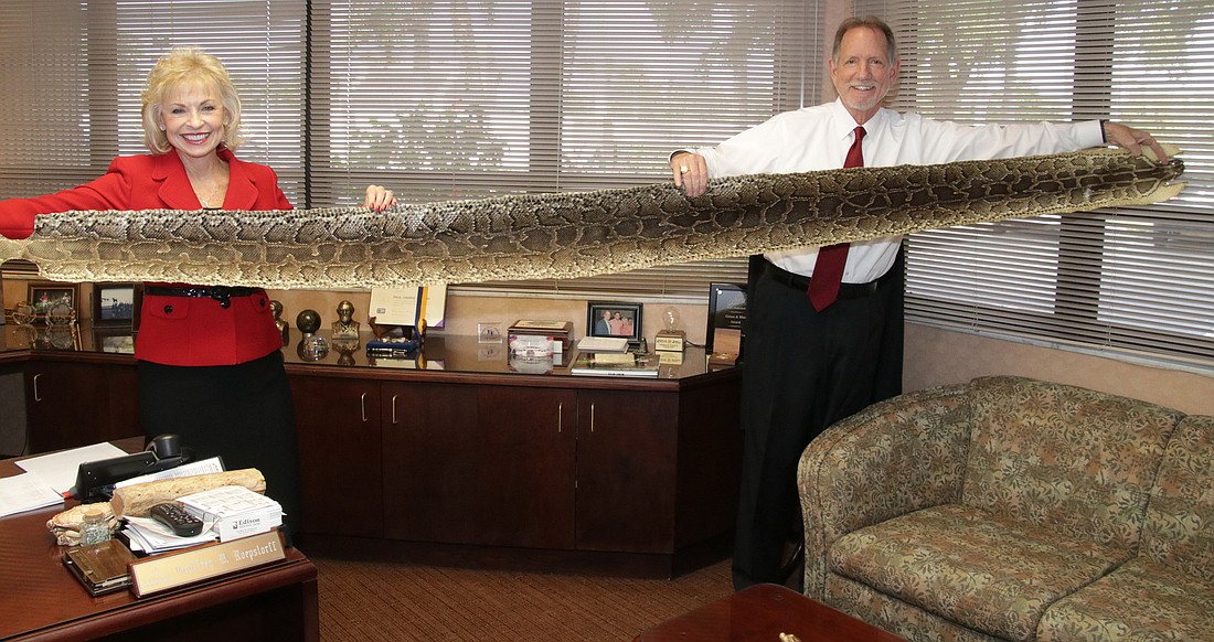Edison National Bank co-founders Robbie and Geoff Roepstorff show off the skin of one of their prized python catches. JimJett.com photo