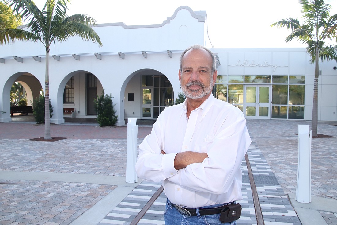 Owen-Ames-Kimball President David J. Dale stands between the railroad tracks that pass right through the recently renovated railroad depot that is now home to the Southwest Florida Community Foundation in Fort Myers.
