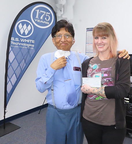 Courtesy. S.S. White Technologies and Shukla Medical owner and CEO Rahul Shukla, left, gives a $1,000 holiday bonus check to staff member Brandi Roche.