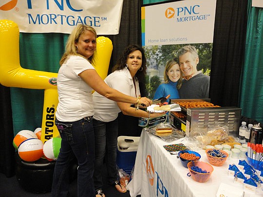 Melanie Younger and Julie Koren of PNC Mortgage cook hotdogs for visitors to their booth.
