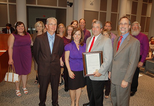 Jim and Donna Bailey, with the staff in the background, accept the Jacksonville City Council's framed resolution from Council President Bill Bishop (right) and member Doyle Carter.