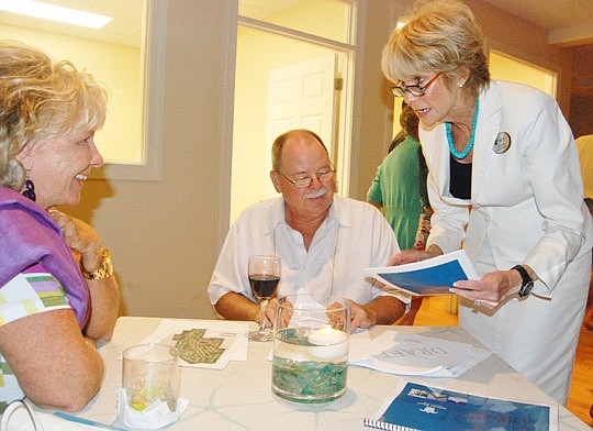 Prudential Network Realty  president Linda Shearer (standing) talks with area residents Melanie and John Green.