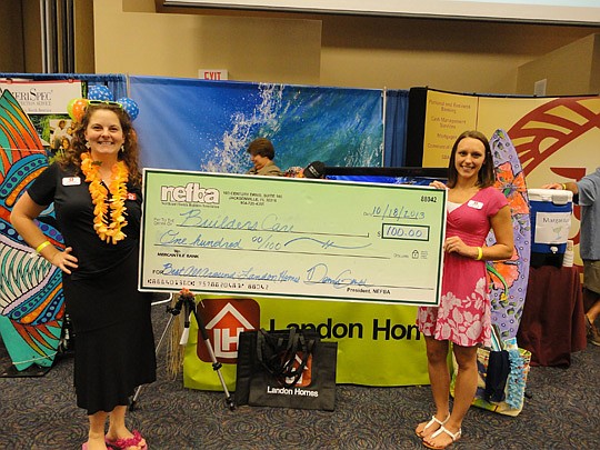 Marnee Oehmann and Nicole Smagala of Landon Homes with the winner's check for having the booth judged Best in Show.