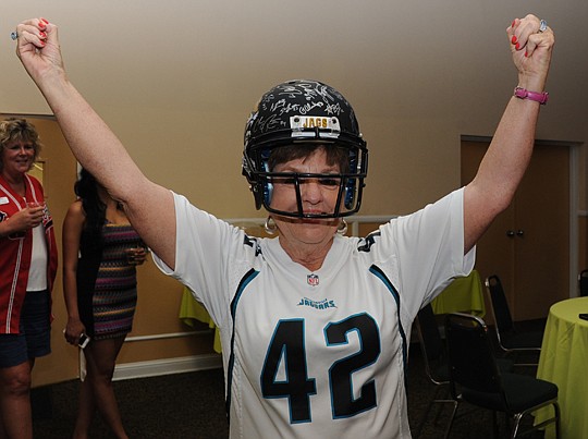 Holly McMurry models an autographed Jacksonville Jaguars helmet and a jersey during the June auction to benefit NEFAR's Realtors Political Action Committee. McMurry is chair of the committee, which lobbies at the local and state levels for Northeast F...