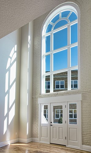 Tall windows from the junior high's old theater and gym (below) became windows that spanned two stories in The John Gorrie's townhomes (above).