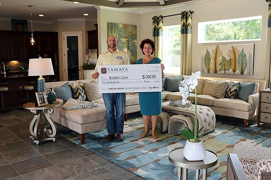 Judith Sisler Johnston, president of Sisler Johnston Interior Design, presents a check to Matt Wilford, executive director of Builders Care. Johnston donated her winnings to the charitable arm of the Northeast Florida Builders Association.