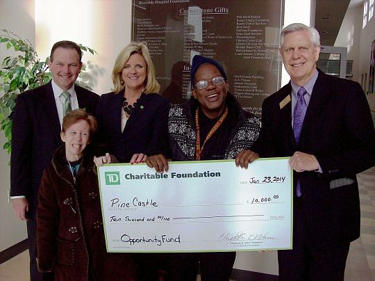 From left, Mike Nursey, TD Bank regional vice president, Cindy Stover, TD Bank market president in North Florida, and Pine Castle Executive Director Jon May (right) join campus program participants Beth and Aaron at the check presentation.