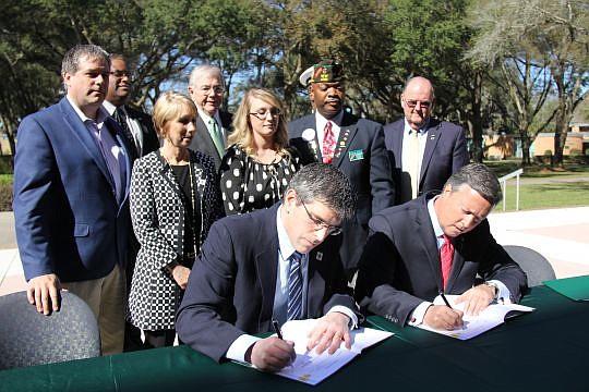 Children of Fallen Patriots Foundation Executive Director John Coogan (left) and Jacksonville University President Tim Cost sign an agreement to make JU the first school in the U.S. to partner with the nonprofit to award scholarships to JU for student...