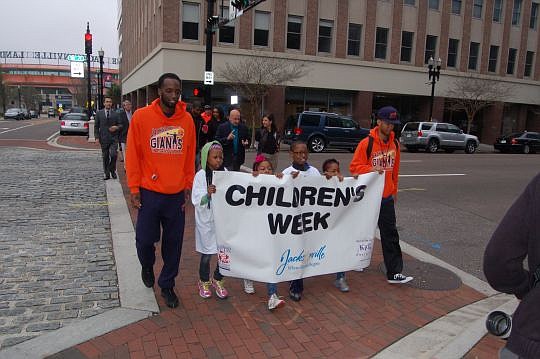 Jacksonville Giants basketball players Brandon Davis (left) and Travis Johnson carried the banner Wednesday for the fifth annual Jacksonville Kids Coalition "Count Your Steps for Children" advocacy walk from the Jacksonville Landing to City Hall, part...