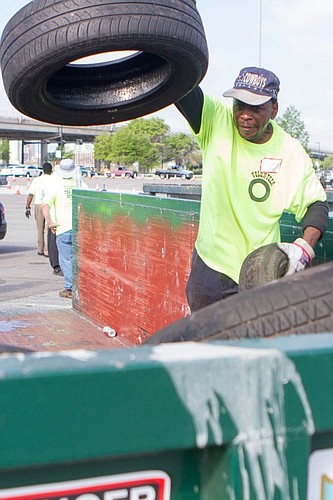 Volunteer Darryl Lindsey stacks tires in a dumpster at the sign and tire buyback event Saturday at EverBank Field.
