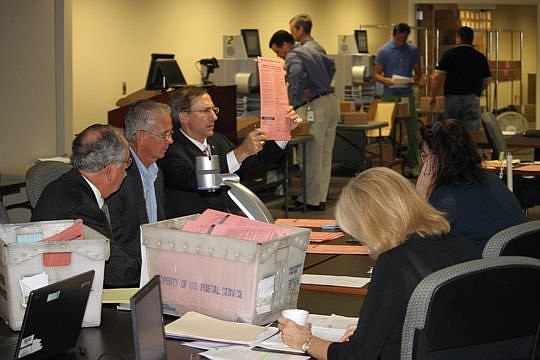 Supervisor of Elections Jerry Holland holds up a provisional ballot for a closer look Wednesday, a day after two local races were too close to name a winner. Tuesday's primary results must be finalized before the state can declare a recount for the St...