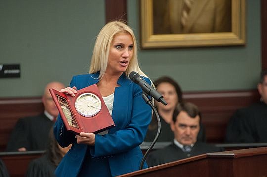 F. Susannah Collins, president of the Jacksonville Women Lawyers Association, gave Aho a clock.