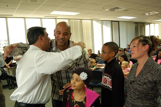 Andre Clark gets a hug from Harvey Bernhardt Foundation Chairman Wes Bernhardt. Clark and his wife, Heather Williams, and their children, Aaliyah and J.J., were among the 30 families who received $1,000 in gift cards from the foundation.