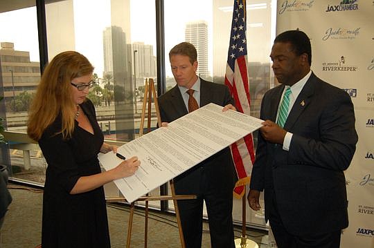 From left, St. Johns Riverkeeper Lisa Rinaman signs a memorandum of understanding outlining a new partnership to preserve the St. Johns River, witnessed by JAX Chamber President and CEO Daniel Davis and Mayor Alvin Brown.