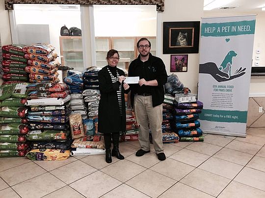 Diana Fox, community relations coordinator for the Jacksonville Humane Society, accepts a check from Carter Simpson of Pet Paradise. The business raised more than $1,000 and donated 2,300 pounds of food to the humane society.