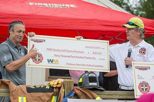 Waste Management CEO David Steiner, left, and Firehouse Subs partner Stephen Joost hold the check celebrating more than $60,000 in donations made to First Coast public safety organizations at the Pond Charity Golf Classic.