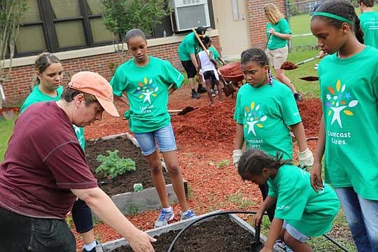 Left, Comcast Manager Laura Montagano directs fellow volunteers working on the garden at Saint Clair Evans Academy.