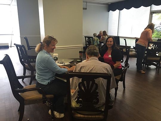 Attorney Hollyn Foster and paralegal Amy Kilgore assist a senior citizen at Cathedral Townhouse.