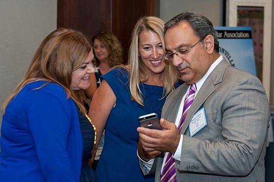 Elizabeth Howard and Katie Dearing look at photos on Michael Bateh's phone before the reception started.