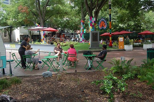 Tables and chairs placed in Hemming Park attract people to have coffee or lunch in the Downtown public space near City Hall and the Main Library.